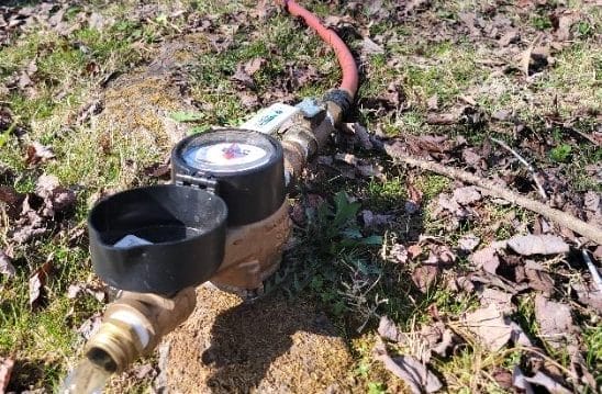 Water Meter With Hose in Grass and Leaves
